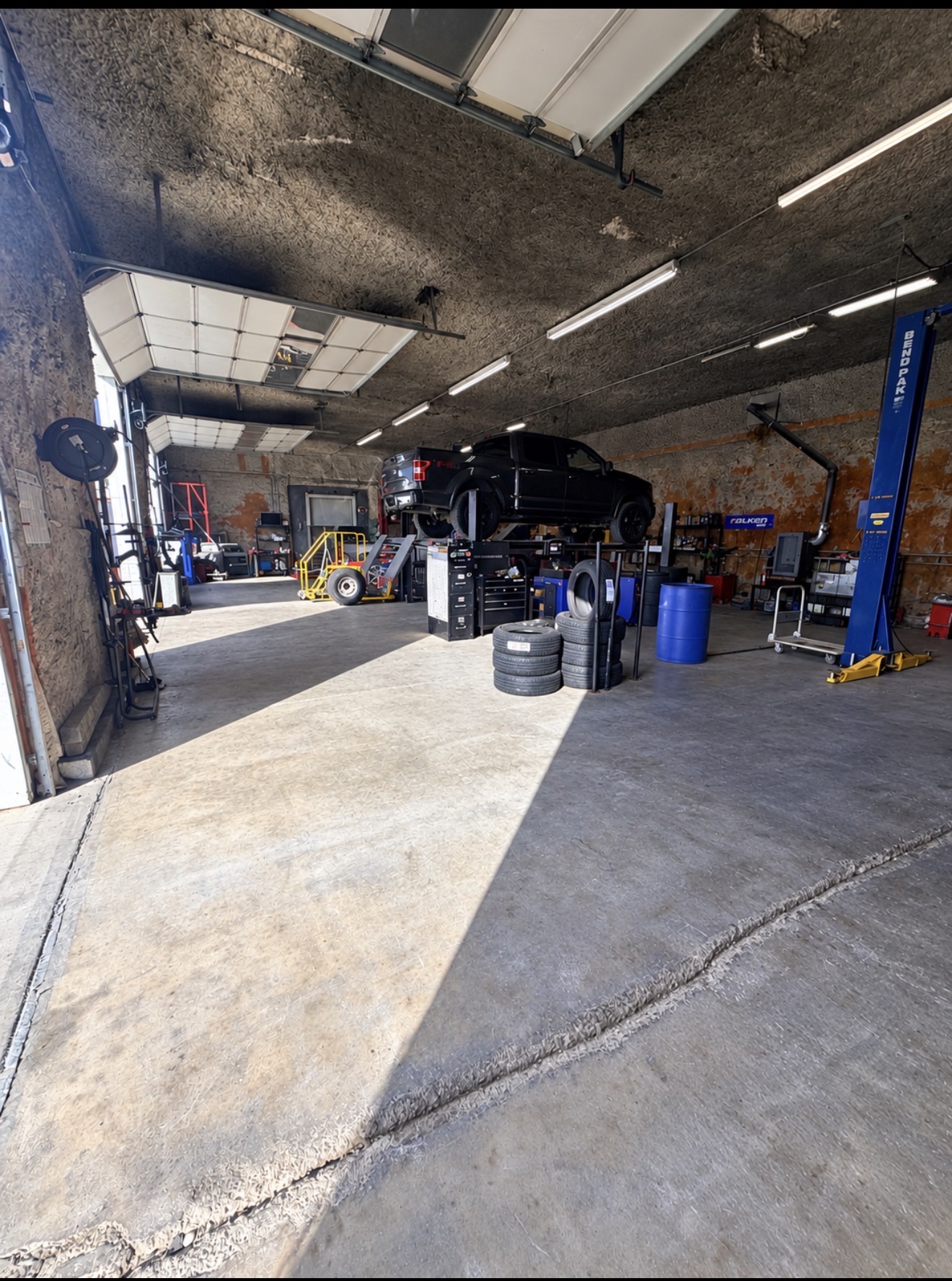 Inside a Choice Tires service bay: a pickup up on the lift with a stack of tires ready to mount