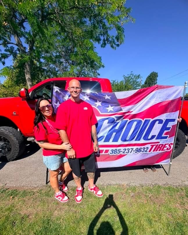 Jaime & Shane Reedy standing in front of the Choice Tires banner at a local event in Grantsville